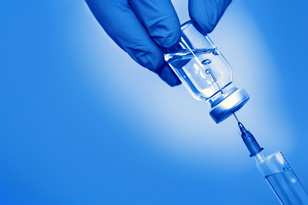 Vaccine in a bottle with a syringe on a blue background.The concept of medicine, healthcare and science